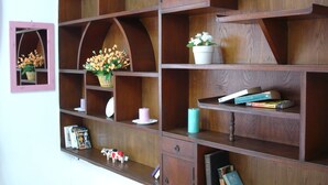 Une étagère en bois, dotée de plusieurs compartiments, dont certains contiennent des livres et des objets décoratifs, comme une petite figurine de vache et une plante en pot.