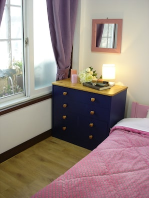 A bedroom with a wooden dresser, a bedside table with a lamp, a mirror, and a pink bedspread. - iCOS Guesthouse 2 for Female - Hostel (Seoul)