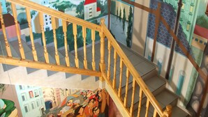 A wooden staircase with a mural of a town scene, including a church and a river. - Hotel Gasthof Goldener Hahn (Frankfurt an der Oder)