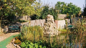 A garden with a stone structure, a green path, and a wooden fence. - Hotel Gasthof Goldener Hahn (Frankfurt an der Oder)