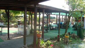An outdoor patio area with tables and chairs under a wooden pergola, surrounded by potted plants and a garden. - Hotel Gasthof Goldener Hahn (Frankfurt an der Oder)