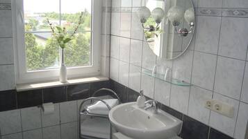 A bathroom with a window, a sink, a mirror, and a towel rack.