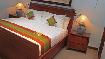 A neatly made bed with a striped bedspread, two bedside tables with lamps, and a wooden headboard.