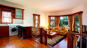 A spacious living area with a sofa, coffee table, and a washing machine in the corner.