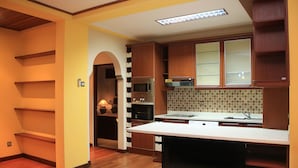 A modern kitchen with wooden cabinets, a built-in oven, and a large island. - Apel Villa Sanur (Denpasar)