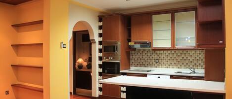 A modern kitchen with wooden cabinets, a built-in oven, and a large island.