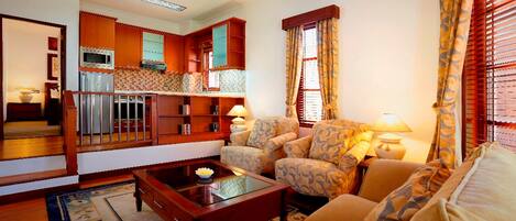 A living room with a sofa, a coffee table, and a kitchen area with cabinets and a microwave.