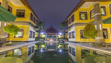 Un hotel con piscina central y fachadas amarillas simétricas.