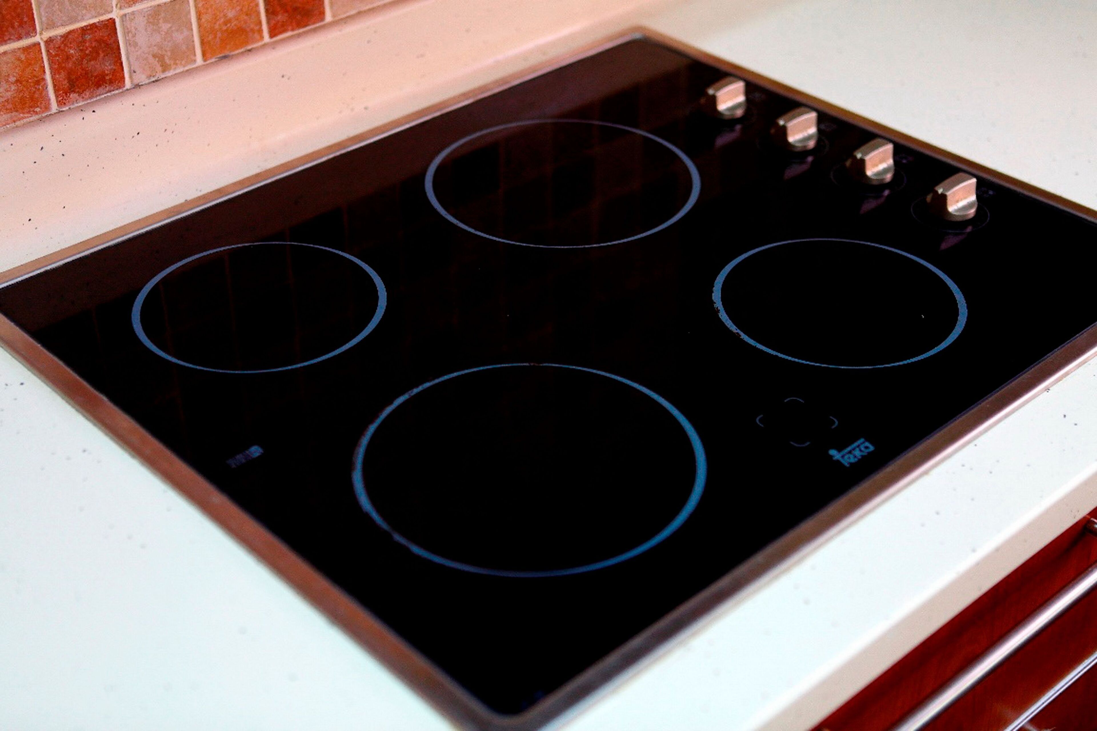 A black induction cooktop with four burners and a digital control panel.