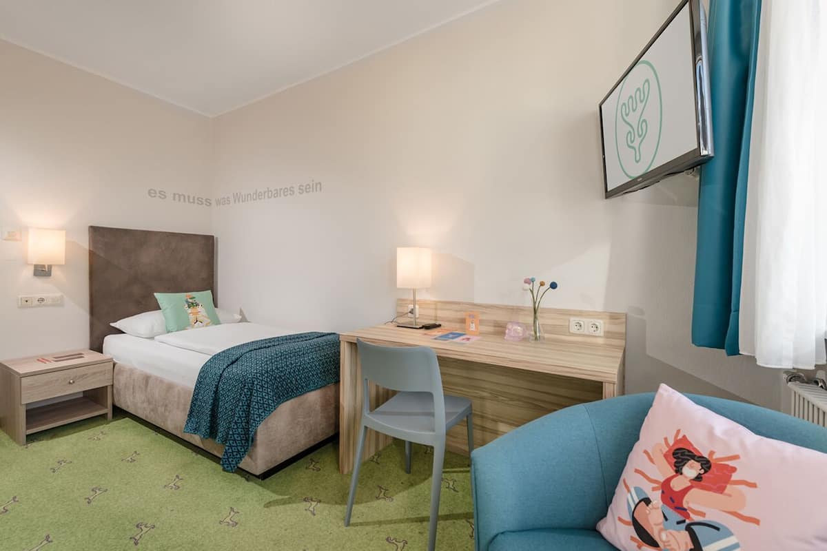 Una habitación de hotel con cama, escritorio, silla y una mesita.