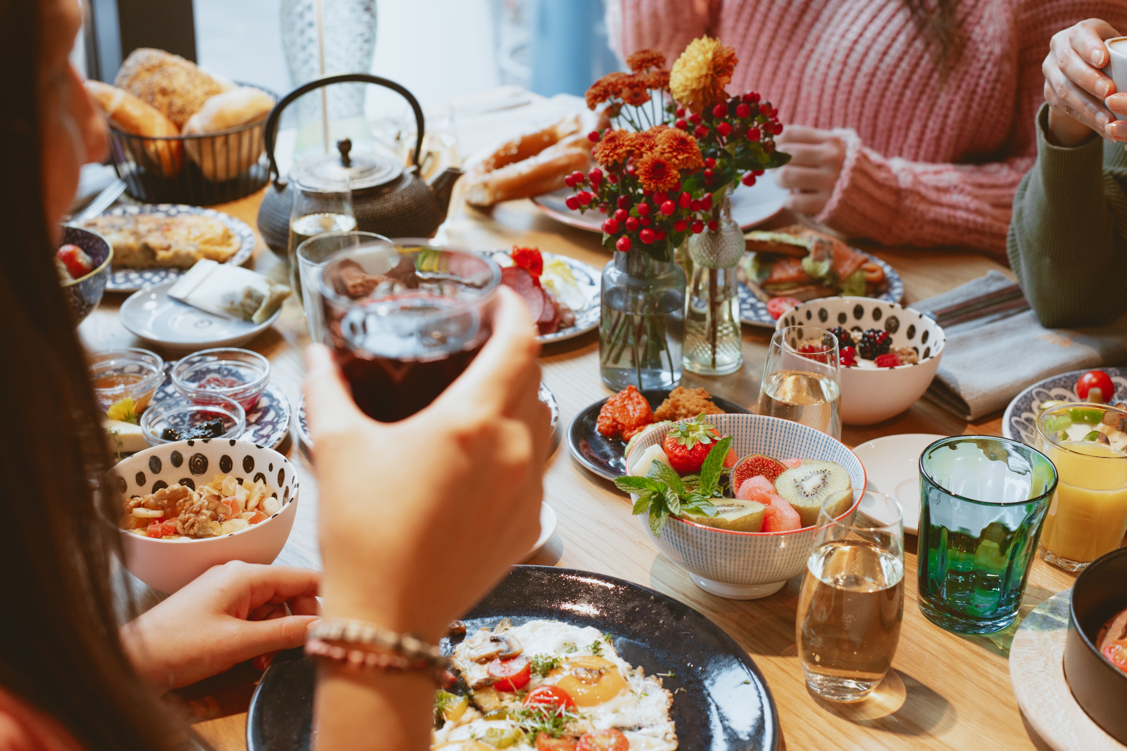 A breakfast setting with various dishes, a teapot, and a vase with flowers.