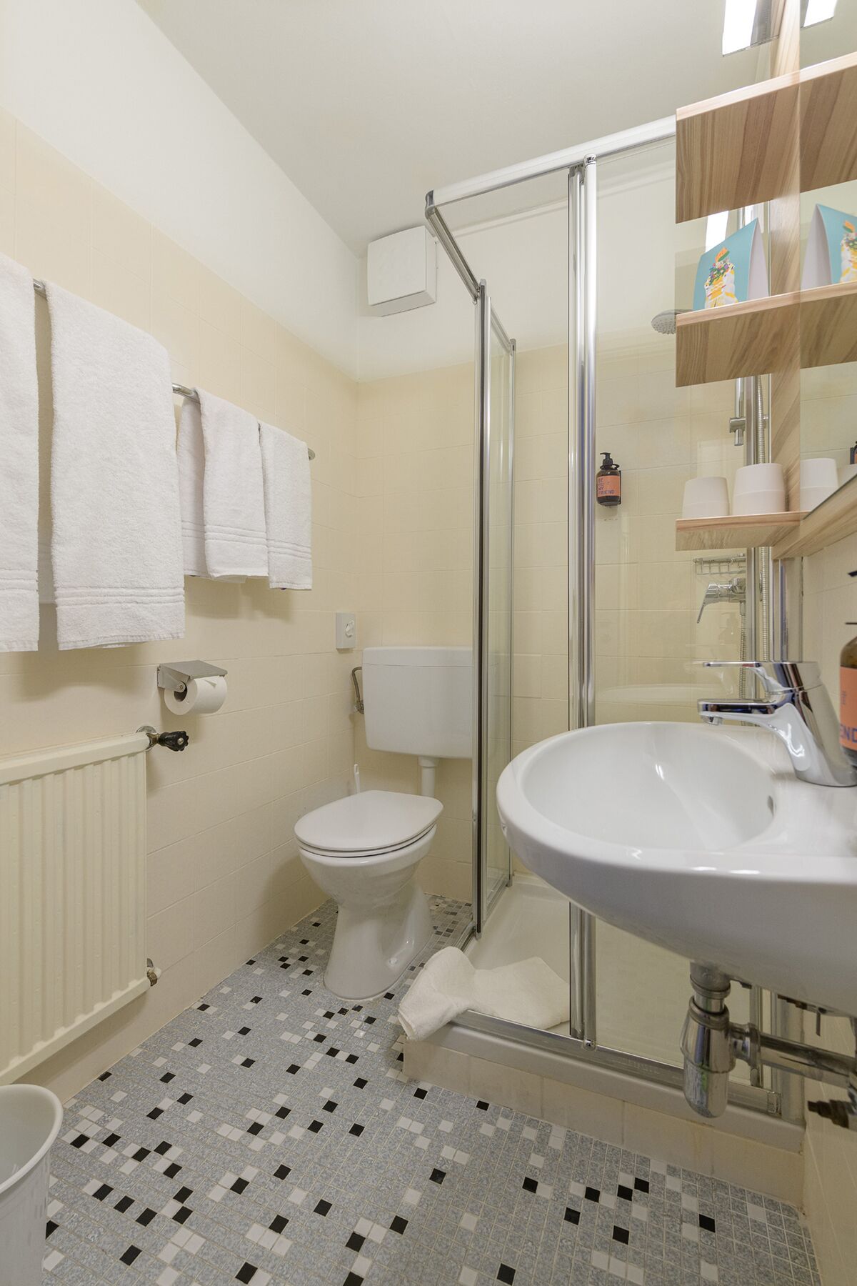 Ein Badezimmer mit Toilette, Waschbecken, Dusche und Fliesenboden.