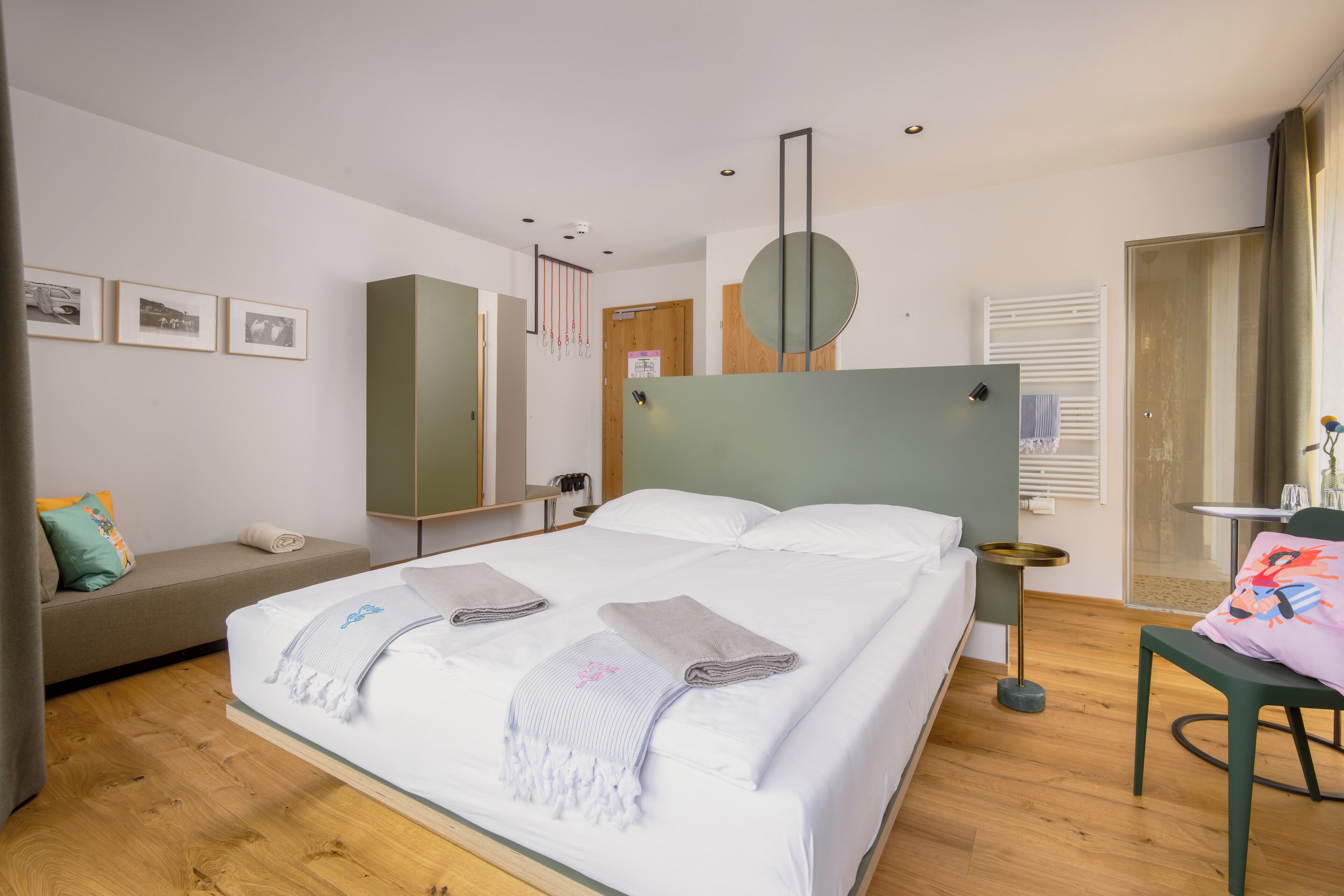 Moderni hotellihuone, jossa on suuri sänky, sohva, pieni pöytä ja peili.