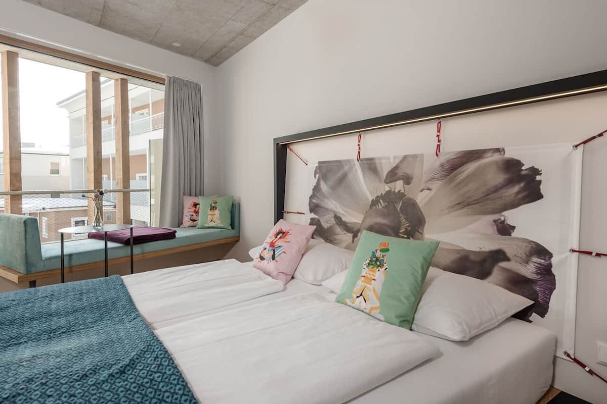 Un dormitorio moderno con una cama grande, vistas al exterior y una pequeña mesa con una silla.