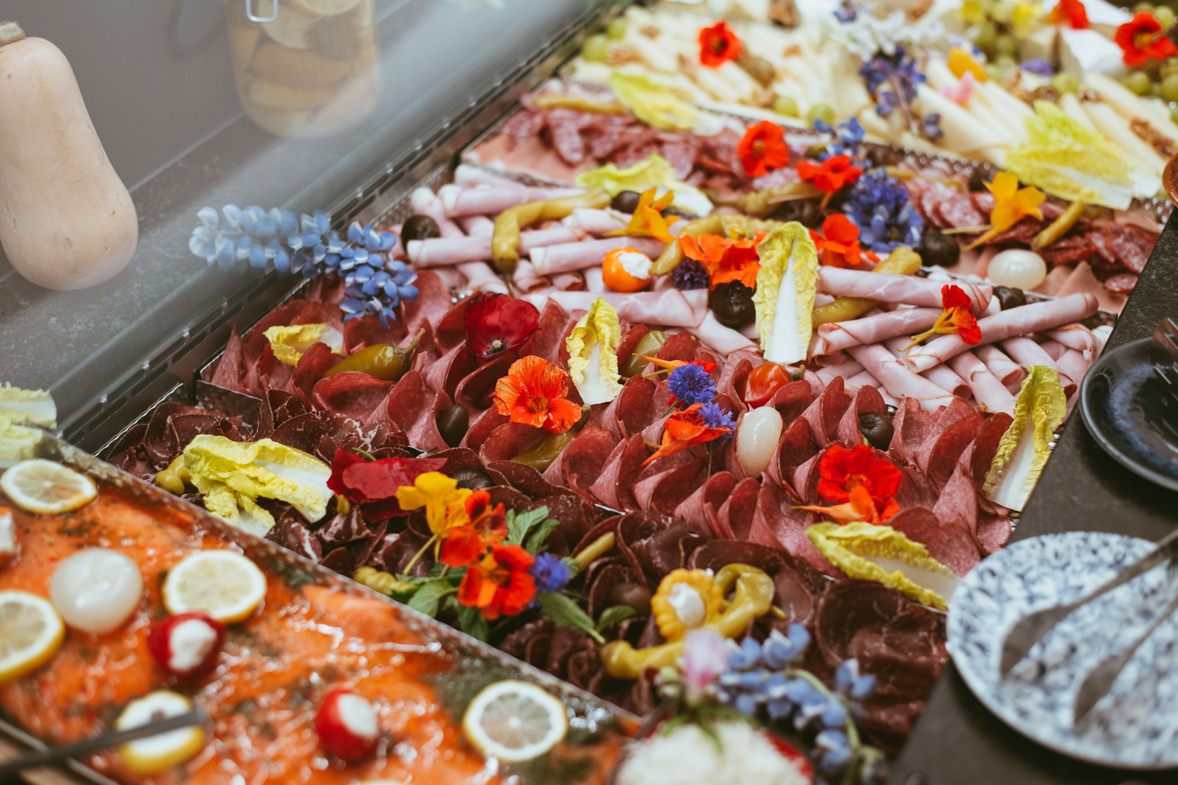 Una tabla de embutidos con diversos quesos, carnes y flores.
