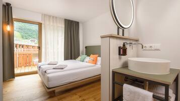 A bedroom with a bed, a bathroom with a sink, and a balcony with a wooden deck.