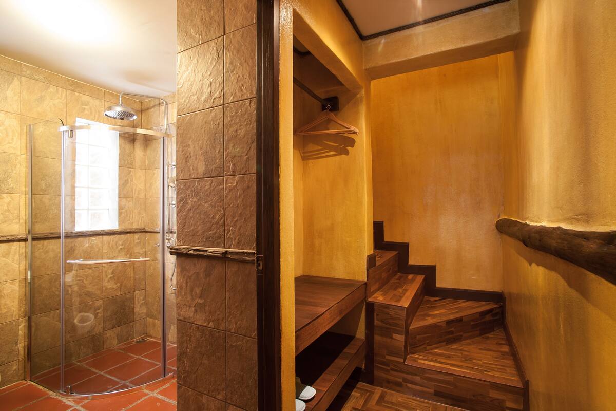 Une salle de bain moderne avec une douche à parois de verre, des marches en bois et un banc en bois.