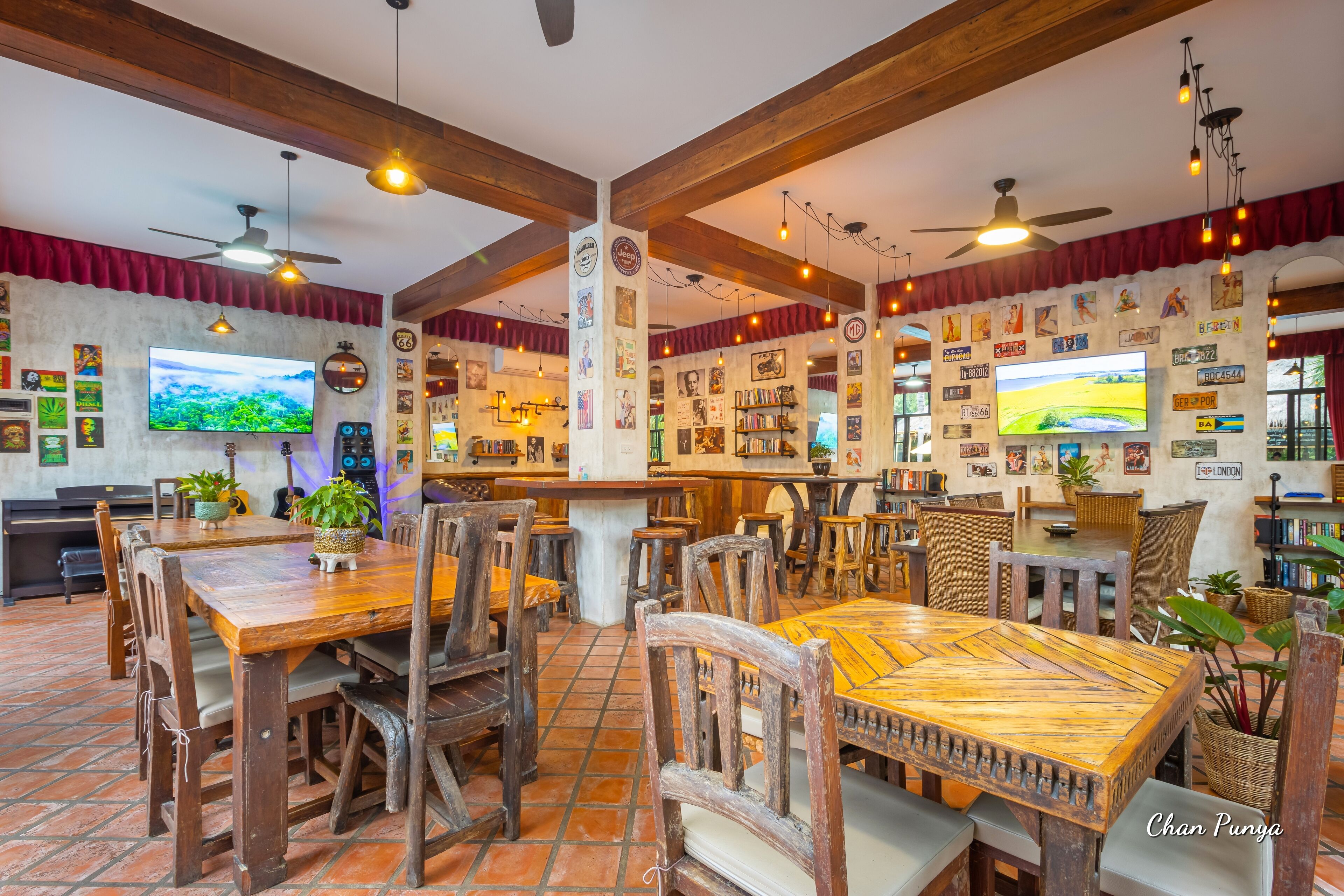 Un restaurant avec des tables et des chaises en bois, un téléviseur et diverses décorations murales.