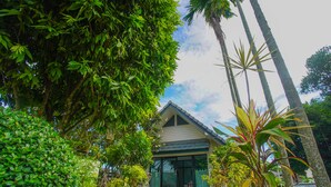 A house with a sloped roof, surrounded by lush greenery and potted plants. - Sang Serene House (Chiang Mai)