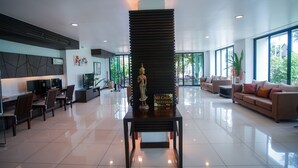 A spacious lobby with a reception desk, seating area, and large windows offering views of the outdoors. - Sang Serene House (Chiang Mai)