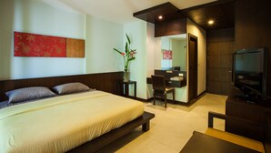 A hotel room with a bed, bedside table, chair, desk, TV, and a potted plant. - Sang Serene House (Chiang Mai)