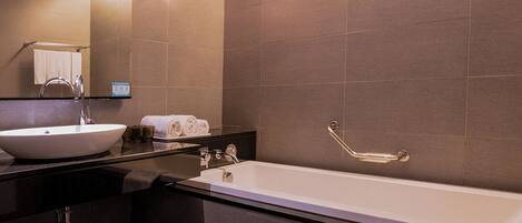 Un baño moderno con una bañera grande, un lavabo y un espejo.