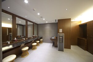 Un baño moderno con un amplio tocador, varios lavamanos y un refrigerador.