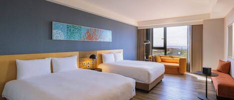 A hotel room with two beds, a sofa, a small table, and a large window offering a view.