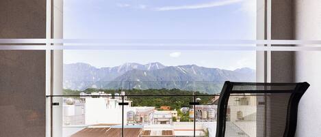A room with a large window overlooking a mountainous landscape.