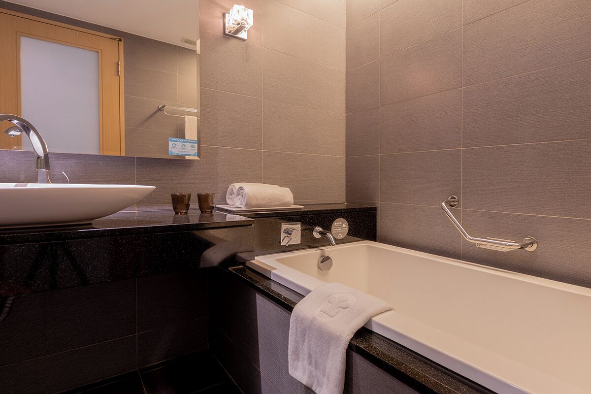 Un baño moderno con un lavamanos grande, una bañera y un perchero para toallas.