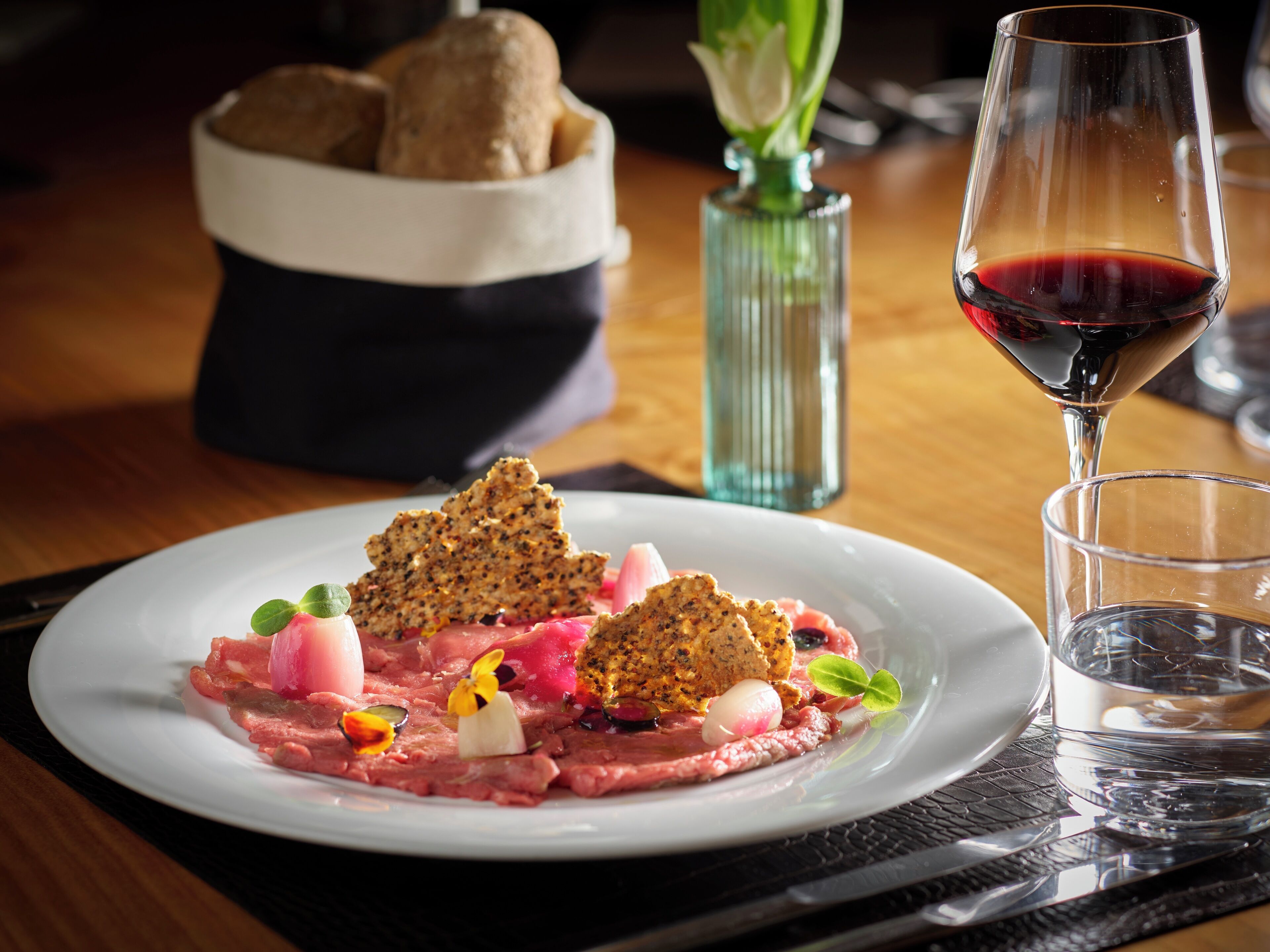A plate of food with a glass of red wine and a glass of water on a table.