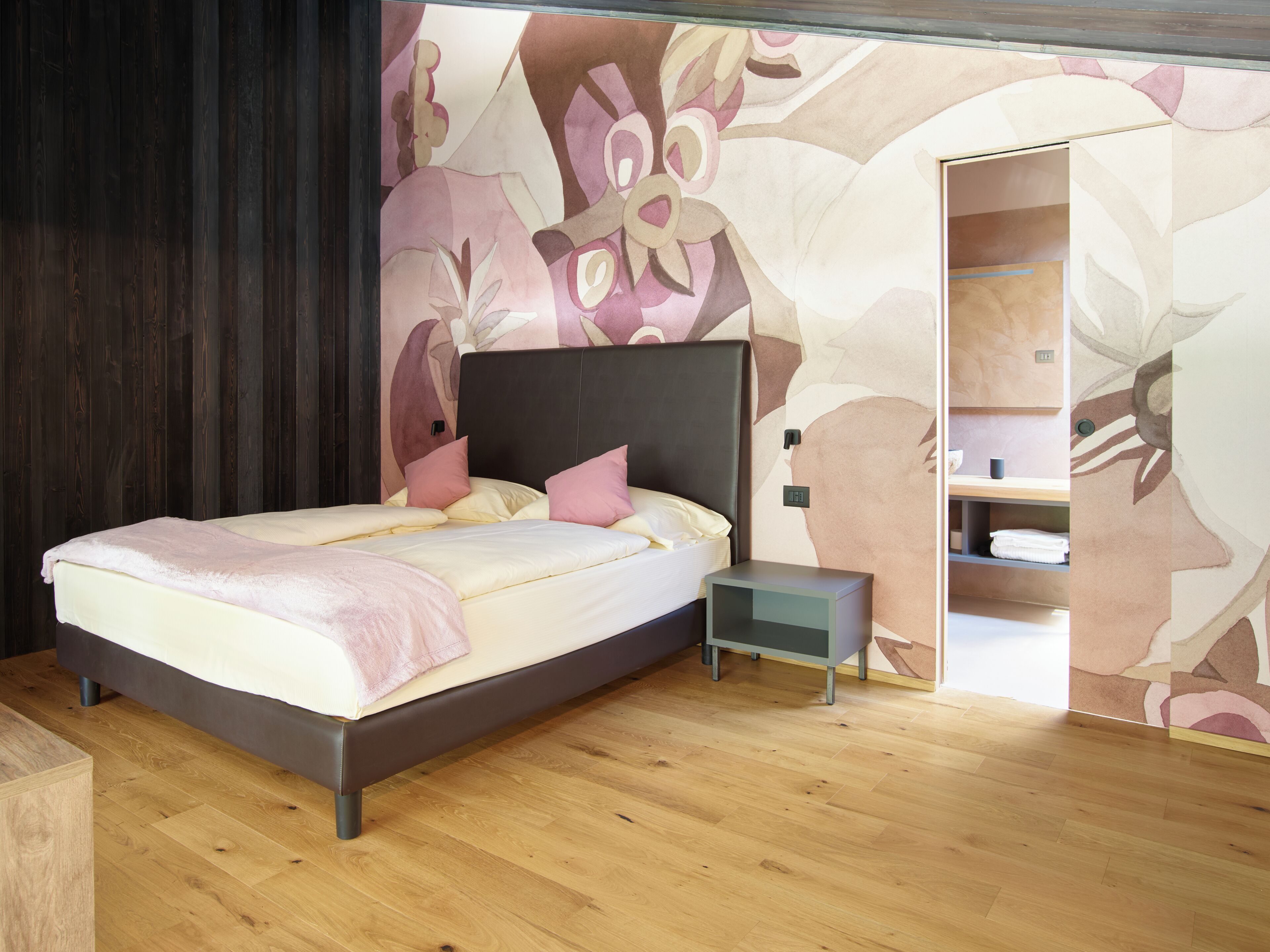 A modern bedroom with a large bed, bedside tables, and a wardrobe.