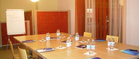 A conference room with a long table, chairs, water bottles, and a whiteboard.