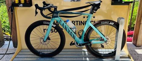 Una bicicleta color aguamarina sobre una plataforma metálica, con fondo amarillo y texto.