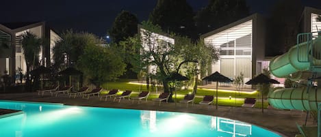 A swimming pool with lounge chairs and a water slide.