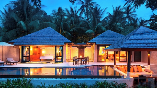 Un resort con dos villas para huéspedes, cada una con balcón, piscina y vista a palmeras.
