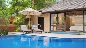 A poolside area with a lounge chair, a small table, and a canopy umbrella.