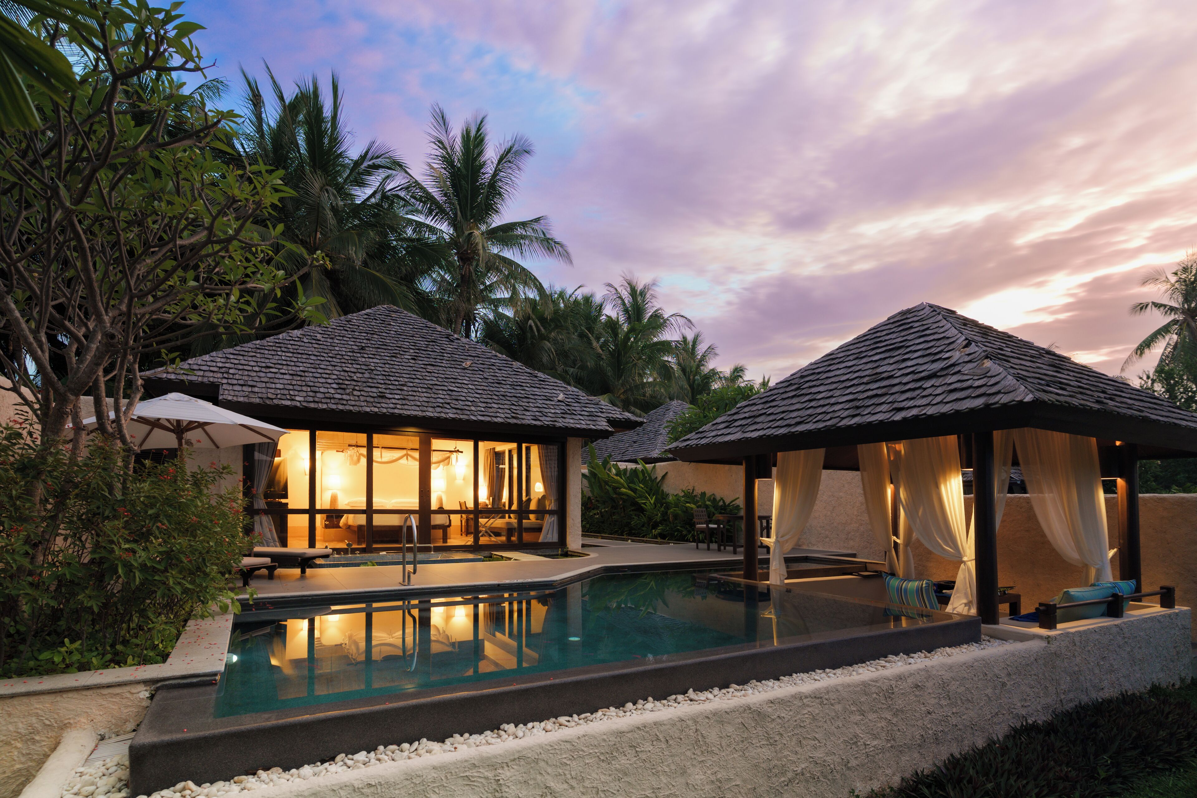 A resort with a pool, two guest houses, and palm trees.