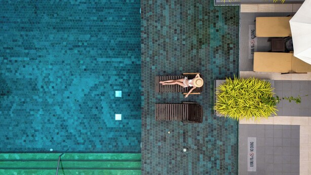 Vue aérienne d’une piscine avec deux chaises longues et une plante en pot.