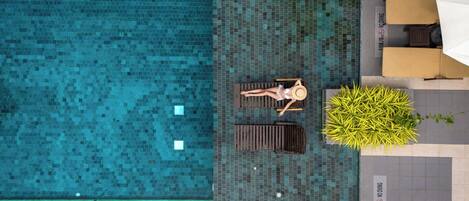 Una piscina al aire libre, sombrillas, sillones reclinables de piscina