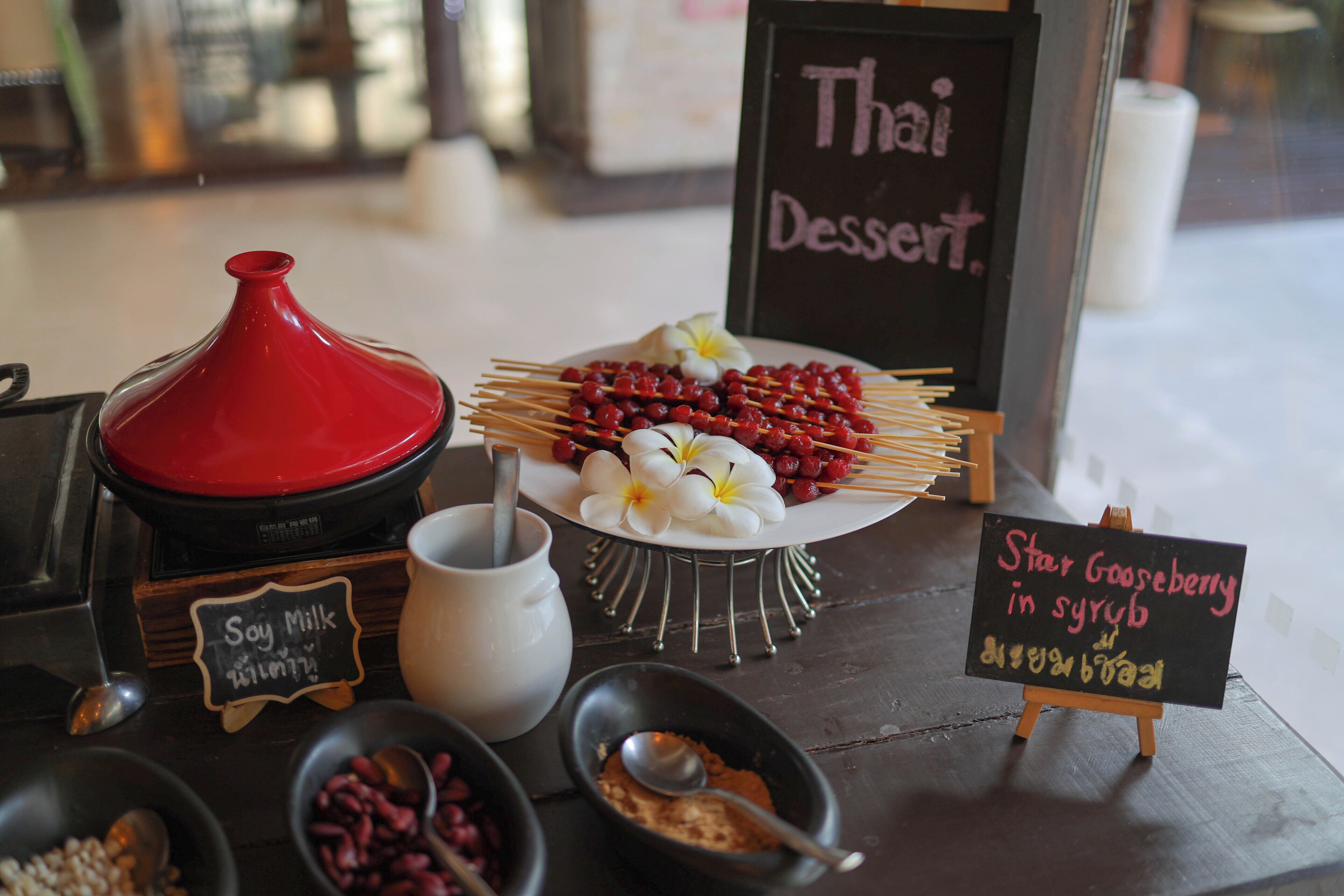 A dessert station with Thai dessert options, including star gooseberry in syrup, and a soy milk drink.