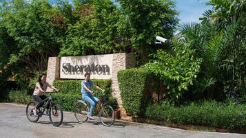 A sign reading "Sheraton" with two cyclists on a road.