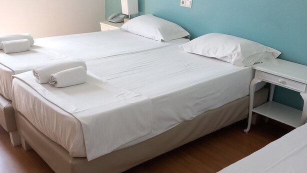 Una habitación de hotel con dos camas, una mesita de noche y un aparador.