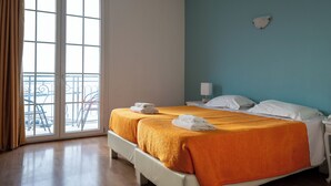 Habitación de hotel con dos camas, un balcón y vista al mar.