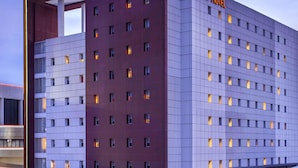A modern hotel building with a prominent 'ibis Hotels' sign, multiple floors, and a grid-like facade. - ibis Surabaya City Center (Surabaya)