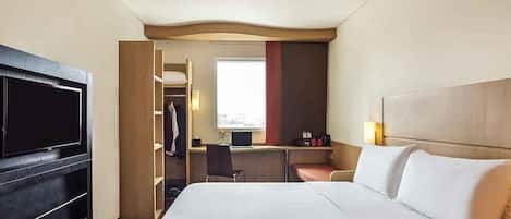 Una habitación de hotel con cama, televisión, escritorio y vestidor.