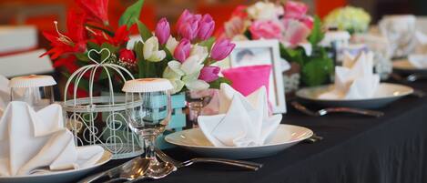 Mesa dispuesta para un evento formal, con centros de flores, copas y servilletas dobladas.