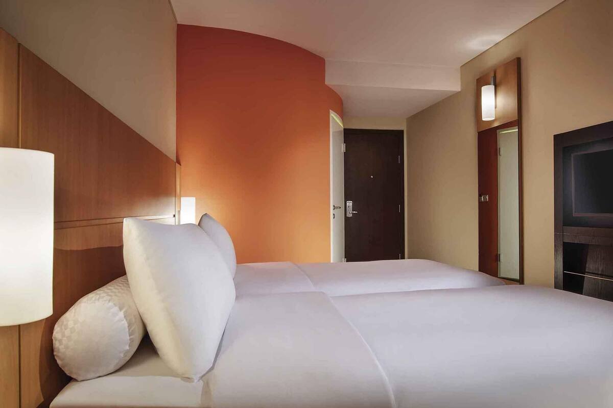 Hotellihuone, jossa on sänky, televisio ja ovi.