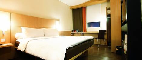 A hotel room with a large bed, bedside tables, a desk, and a chair.