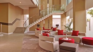 A spacious lobby with a modern staircase, comfortable seating areas, and a large window providing natural light. - ibis Surabaya City Center (Surabaya)
